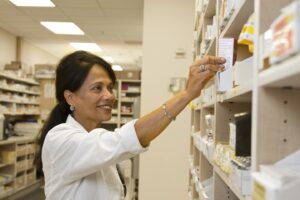 A female pharmacist is selecting a drug from the pharmacy inventory.