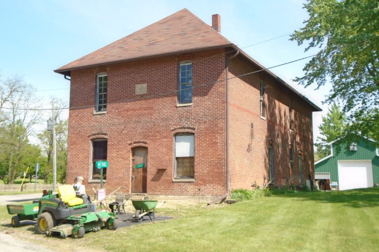 a man riding a lawn mower in front of a brick building