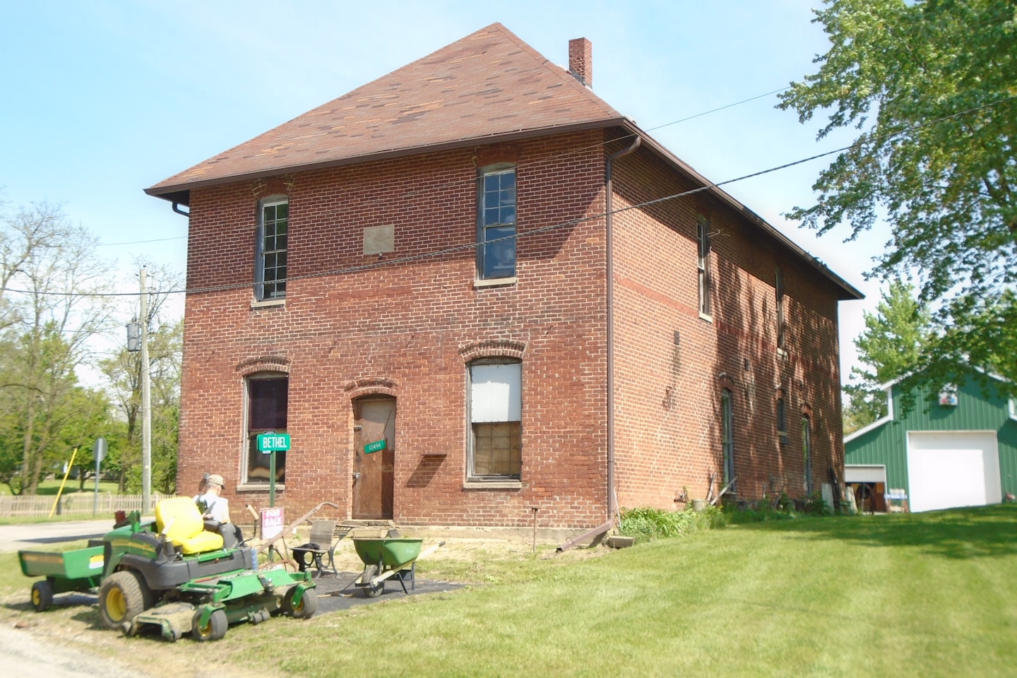 a man riding a lawn mower in front of a brick building