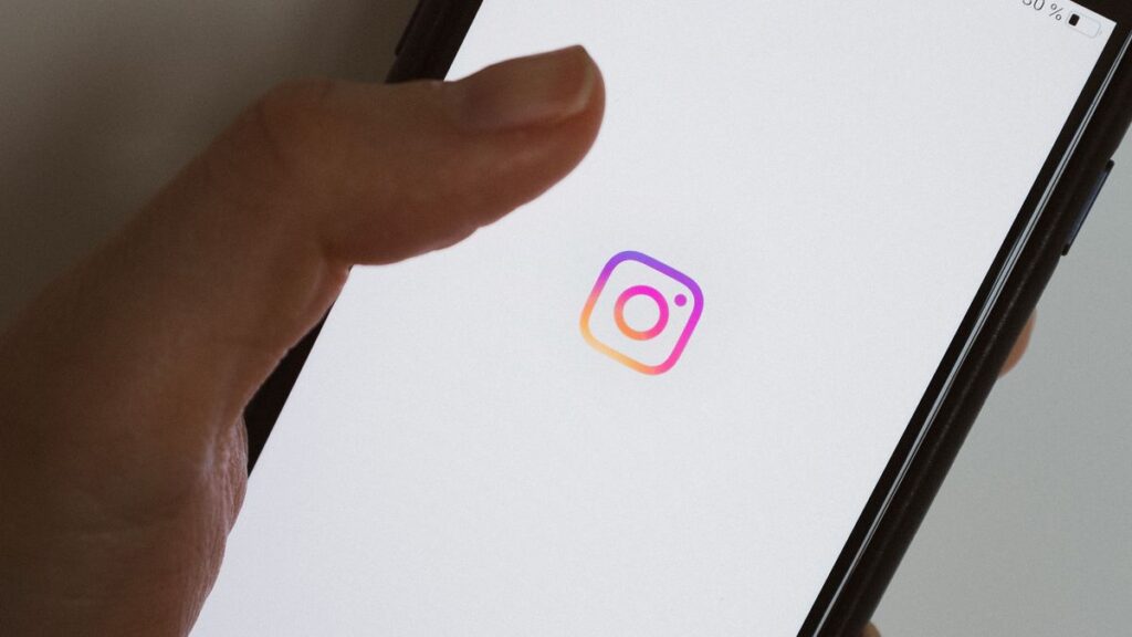 Smartphone affichant le logo Instagram tenu en main